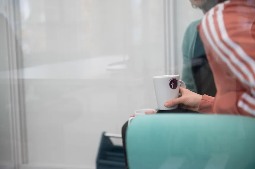 Eine Person hält eine Kaffeetasse mit EVHN-Logo in der Hand