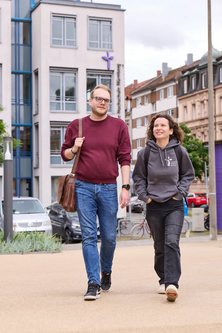 Zwei Studierende laufen auf einem Platz vor der EVHN