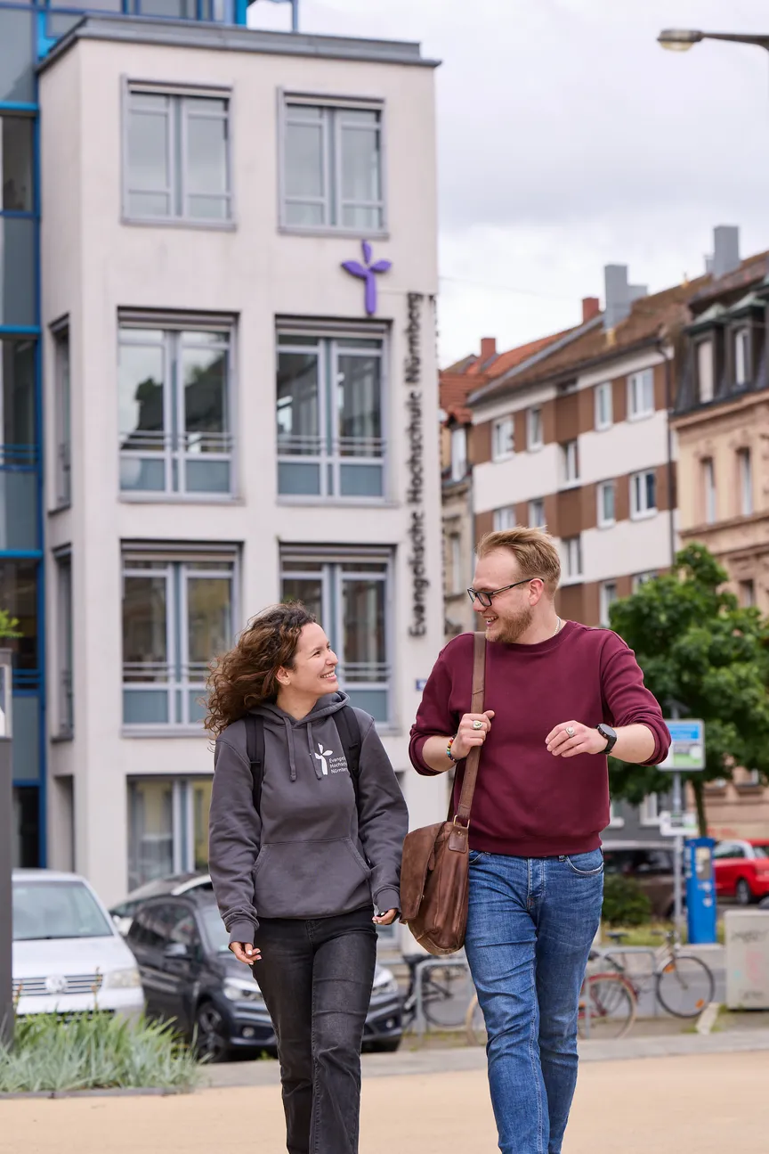 Zwei Studierende laufen auf einem Platz vor der EVHN