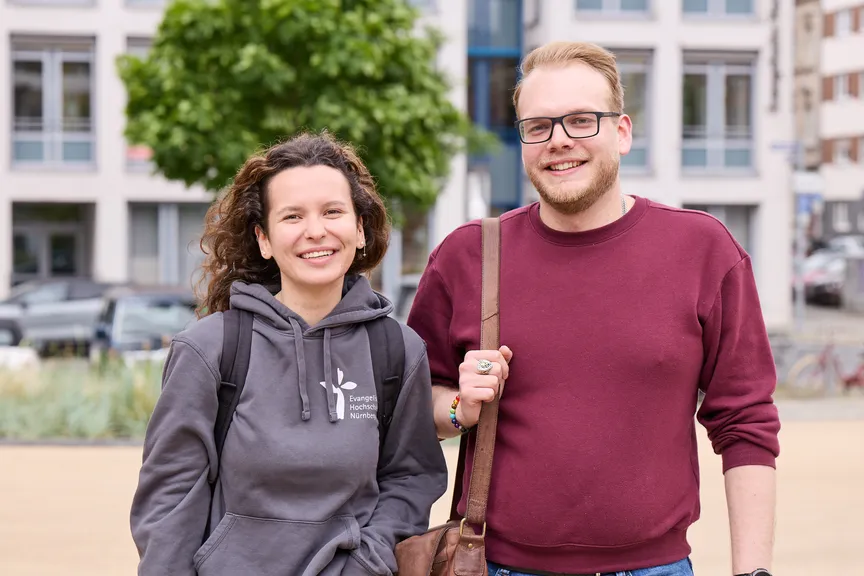 Zwei Studierende stehen auf einem Platz vor der EVHN