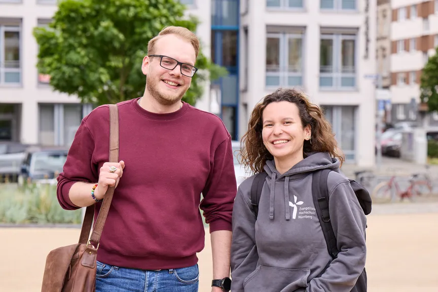 Zwei Studierende stehen auf einem Platz vor der EVHN