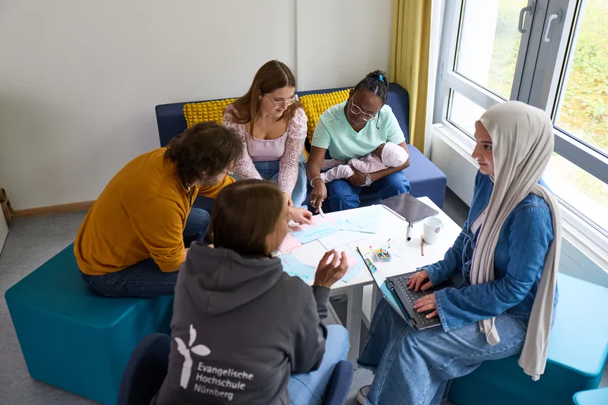 Einige Studierende sitzen in einer Sitzgruppe und unterhalten sich