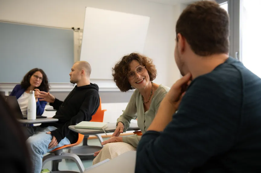 Ein Studierender unterhält sich mit einer Dozentin in einem Seminar
